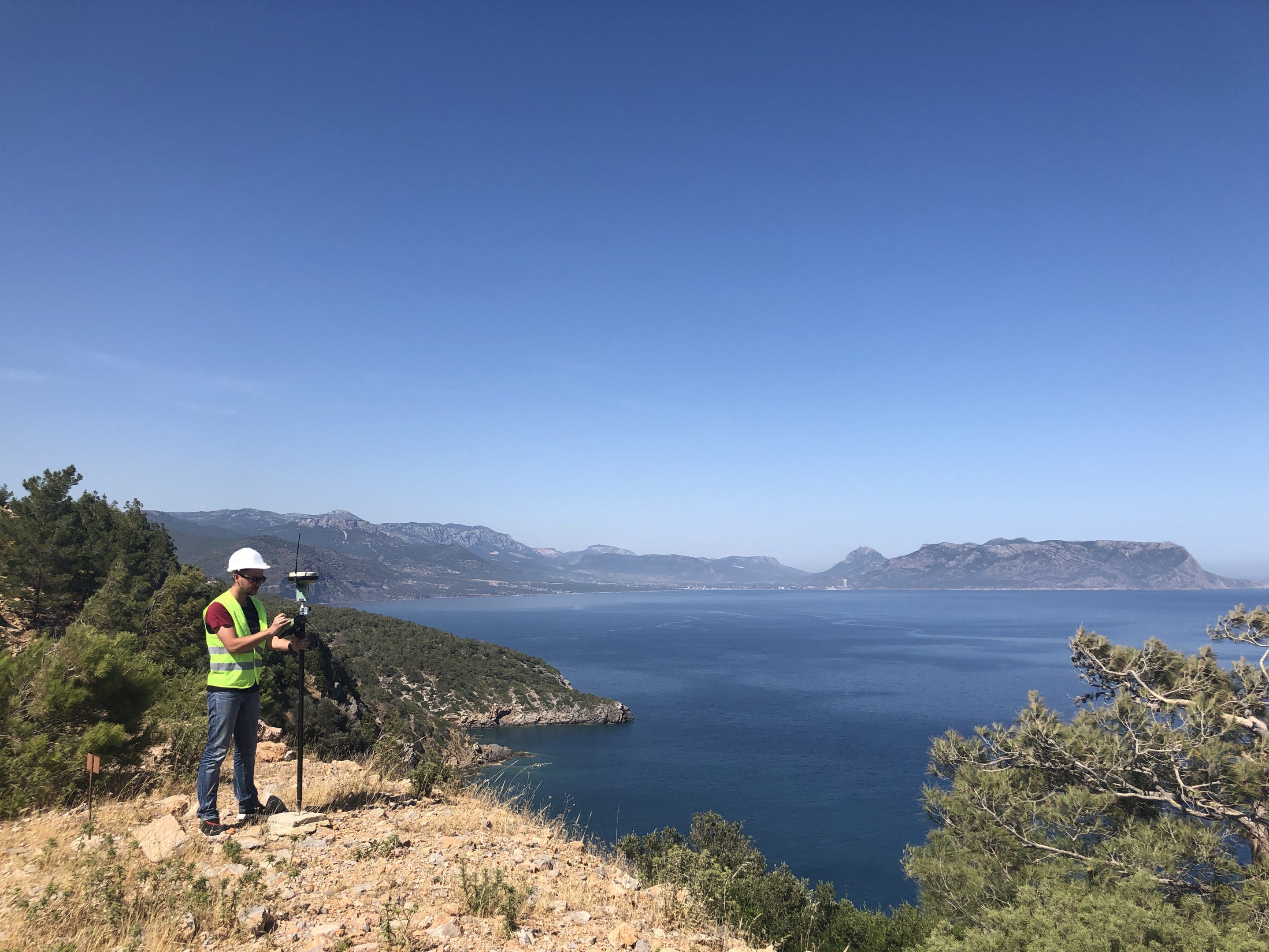 Un topógrafo inspeccionando las colinas que rodean un gran lago.