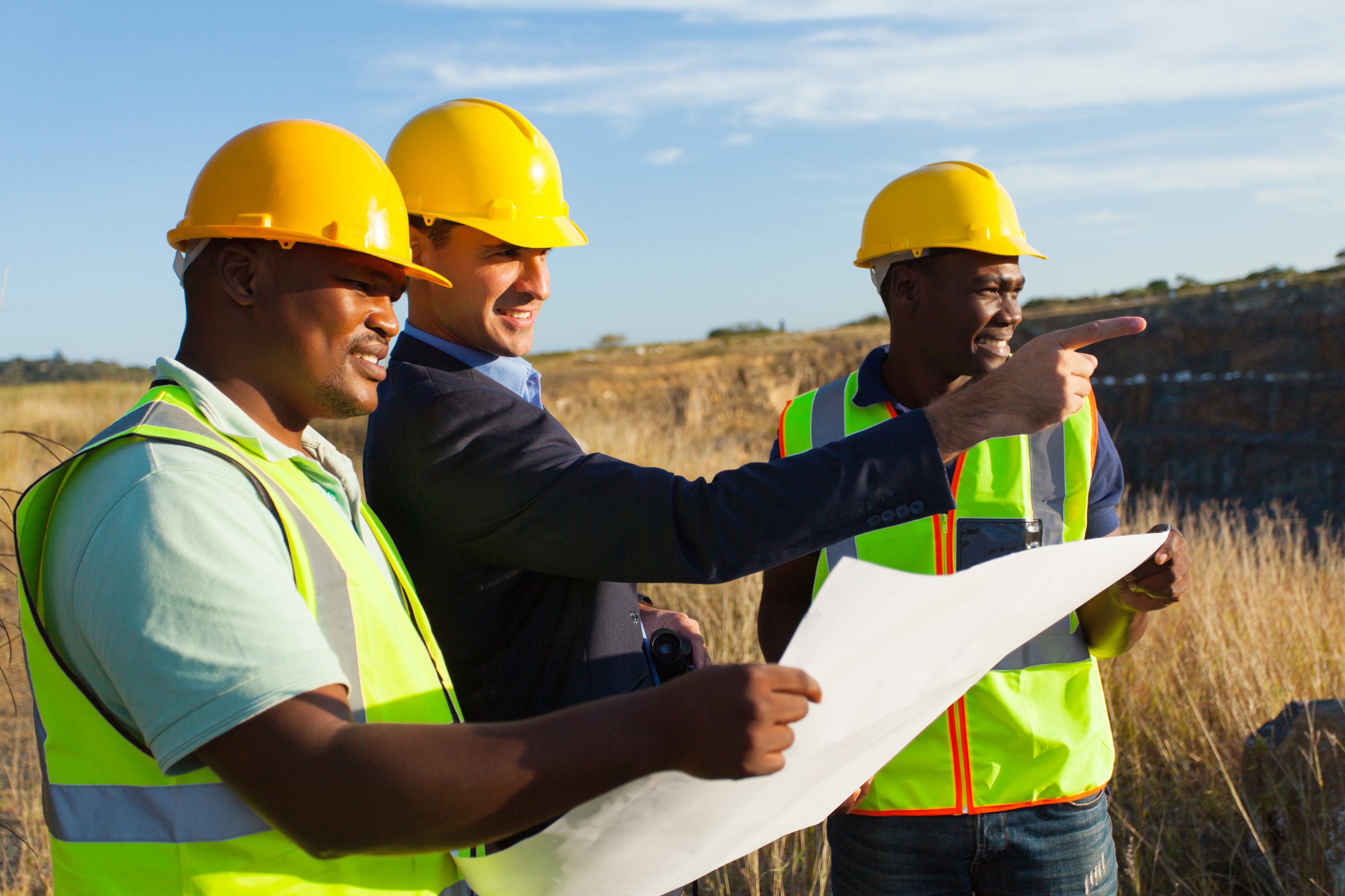 A group of conservation planners reviewing plans at an outdoor work site.