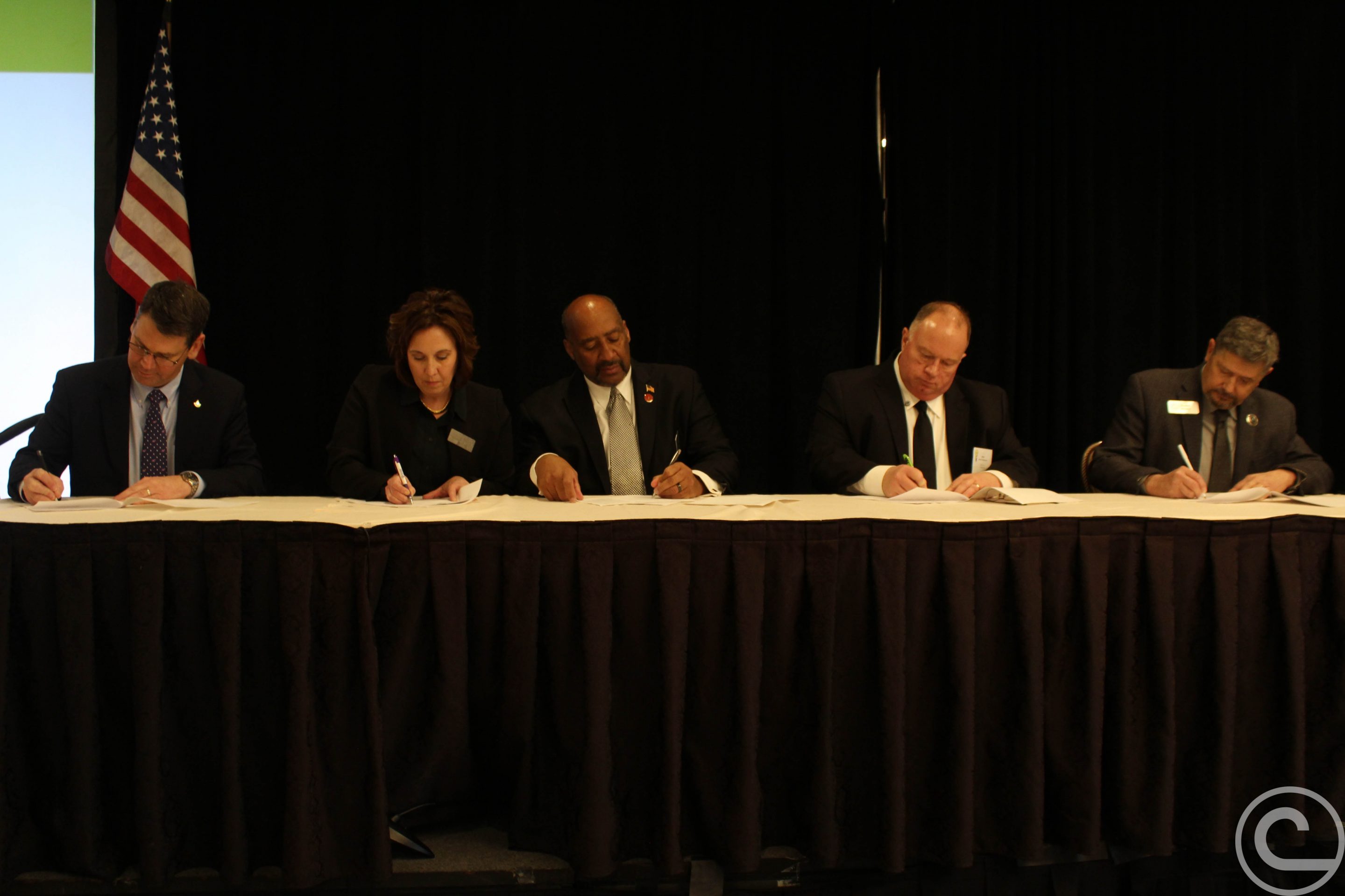 A group of people sitting a table signing contracts.